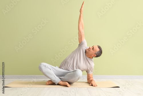 Mature man doing yoga on ma...