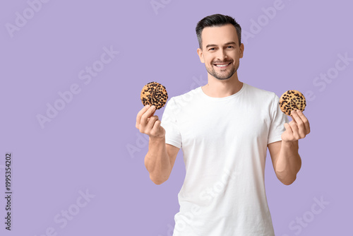 Handsome man with tasty cookies on lilac background