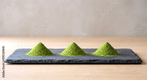 Three mounds of organic matcha green powder on black slate stone, Japanese tea ceremony concept.