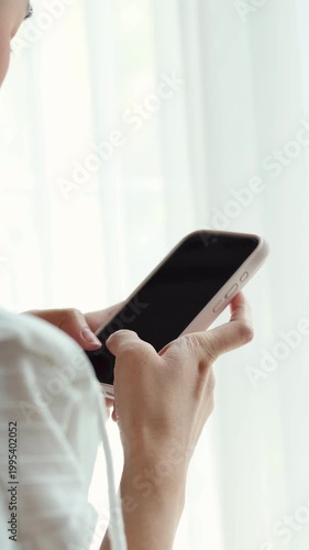 A woman's hand skillfully operates a smartphone in natural indoor light. concept of social media communication, digital transactions, and a lifestyle constantly connected to technology. 4K vertical