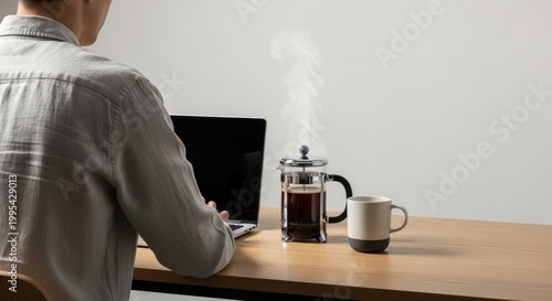 Person Enjoys Coffee While Working on Laptop in Minimalist Workspace