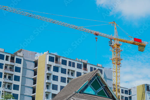 Fotografija The image shows a high-rise building construction project underway using a crane, under a clear blue sky with few clouds