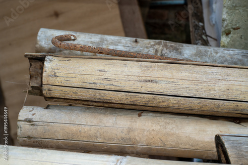 Dry split bamboo poles and a rusty metal hook resting together