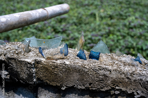 Sharp broken glass pieces embedded on top of a concrete wall