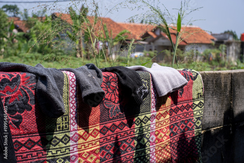 Socks and a patterned blanket drying on a concrete wall