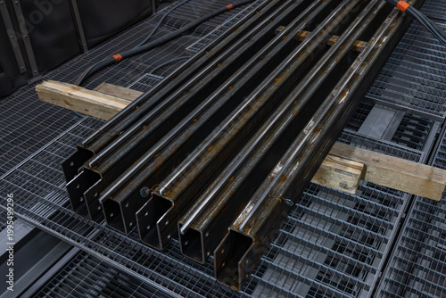 Alignement de profilés métalliques en acier sur cales en bois dans un atelier de fabrication pour la préparation de charpentes industrielles.