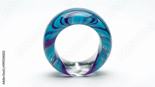 Close-up of a thick transparent glass ring with swirling internal patterns of turquoise blue and deep purple, isolated on a white background with soft shadows and reflections.