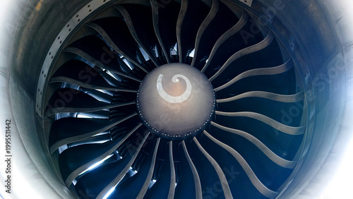 Inside view of jet engine turbine fan blades showing the white spiral on the nose cone spinner of a commercial airplane for aviation technology concept