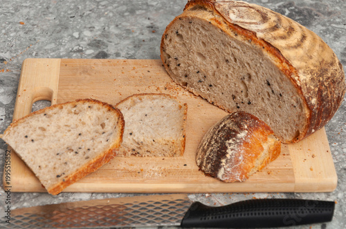 Slices of bread with a long knife on a wooden cutting board.