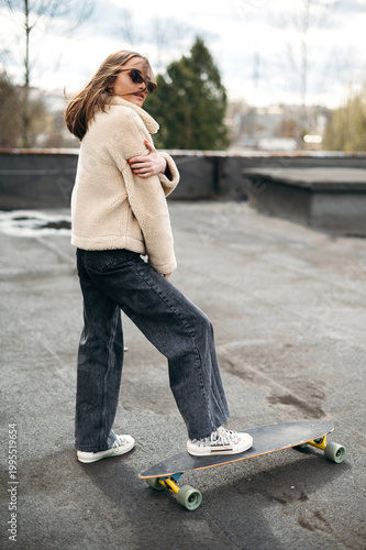 Confident young posing with skateboard on roof top