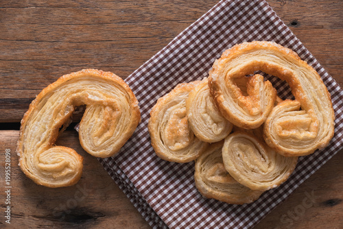 Top view of golden-brown palmier puff pastry with detailed sugary flaky layers, set on rustic wood table