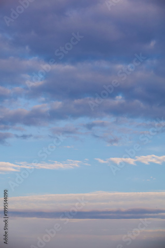 Beautiful pastel sky with soft purple and blue clouds at sunset. Vertical heaven background