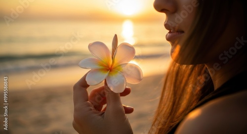 Woman holding flower on beach at sunset