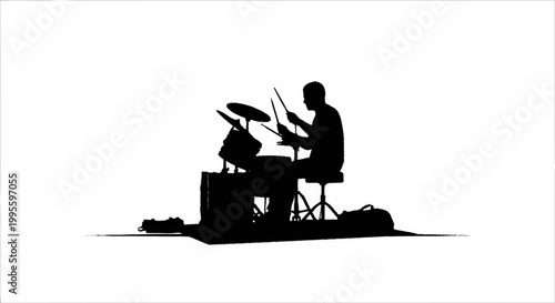 A silhouette of a man playing a drum set in a studio