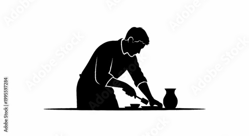 A man in silhouette is working on a pottery project at a table