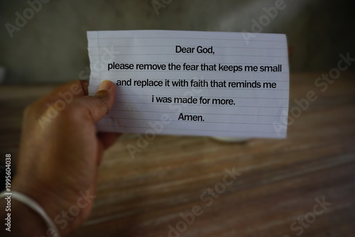 Prayer text on a paper in hand - Dear God, please remove the fear that keeps me small and replace it with faith that reminds me i was made for more. Amen. Christian prayer.
