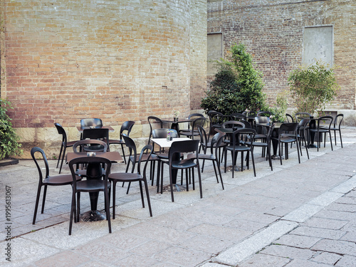 Outdoor café tables and chairs in historic courtyard with brick walls