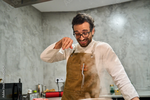 Φωτογραφία Man seasoning food with steam in kitchen
