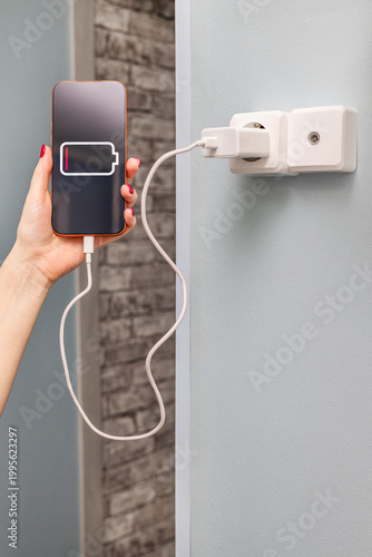 A woman charges a smartphone, vertical photo. A woman charges a smartphone, close-up. dead smartphone battery. charging a phone from the power grid. Vertical photo