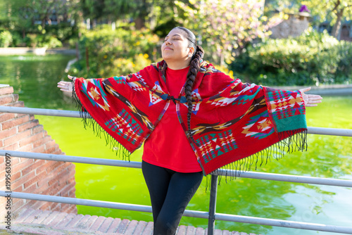 Latin American woman wearing a traditional poncho, finding peace and freedom in the park