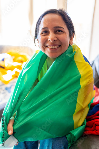 Latin woman smiling and celebrating soccer, wrapped in a Brazil flag