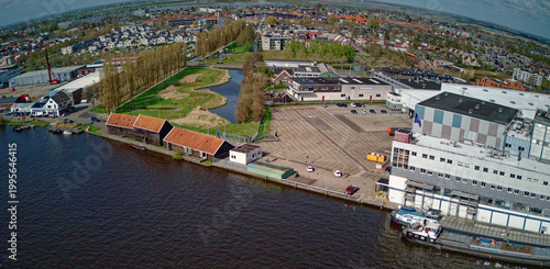 Wormer, Netherlands - 10 April 2026: Aerial view of a red Electric pusher tug carrying white containers with batteries docked beside the Olam International Cacoa factory.