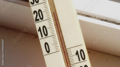 Close up of dusty outdoor thermometer on window with rising mercury on sunny day.
