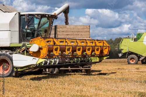The concept of planting and harvesting a bountiful harvest. Agricultural machinery. Agricultural industry. A combine harvester picks up golden ears of ripe wheat.