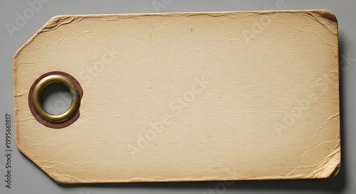 Vintage paper tag with metal ring on gray surface for labeling