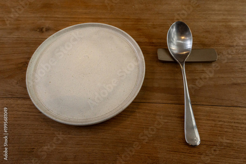 Tablou pe pânză Empty Ceramic Plate and Spoon on Rustic Wooden Restaurant Table