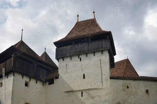 Towers with tiled roof of fortified church in Viscri village against cloudy sky, Transylvania, Romania. Copy space. Close-up.