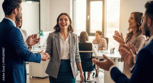 Joyful businesswoman receiving appreciation and handshake from colleagues during team celebration for professional achievement and career success in modern office