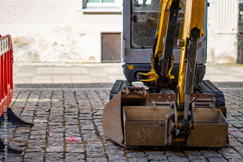 Foto Yellow mini excavator parked on a historic cobblestone street, professional cons