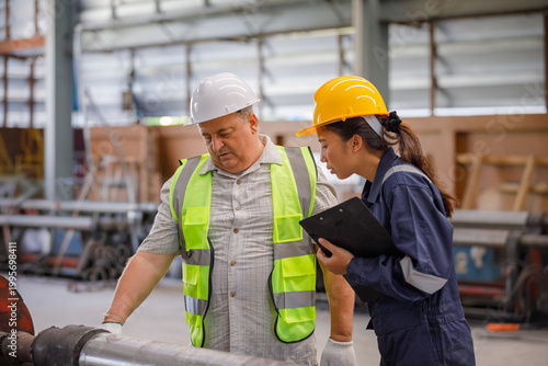 In an industrial plant, a supervisor is measuring metal pipes with a tape measure while a technician records the data, emphasizing accuracy, inspection, and quality control.