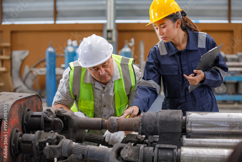 Supervisors and technicians inspect and check machine parts in the factory, with a focus on maintenance.