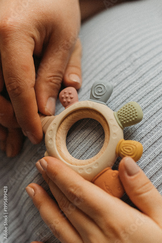 Foto Hands holding baby teething toy on pregnant belly, ожидание малыша concept, clos