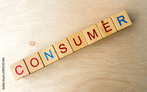 Scrabble tiles spelling 'consumer' on wooden background representing consumerism concept