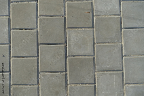 Texture of square brick-like gray concrete pavement with stack bond layout