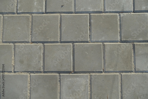 Texture of square brick-like gray concrete pavement with stack bond layout
