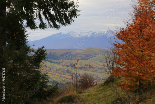 Autumn mountain landscape with snow-capped peaks and colorful trees