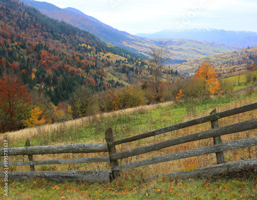 Autumn mountain landscape with rustic wooden fence and colorful foliage