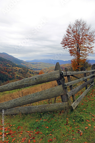 Rustic wooden fence overlooks a vibrant autumn valley with distant mountains