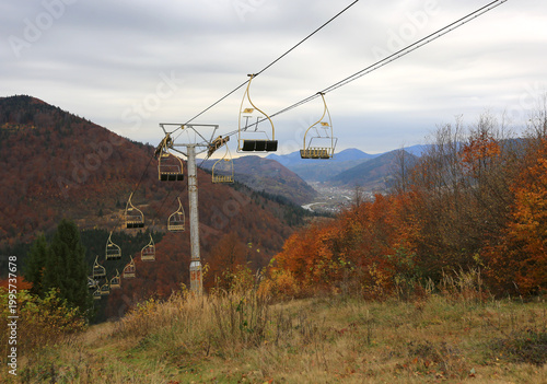 Autumn mountain landscape with an empty ski lift ascending the colorful slopes