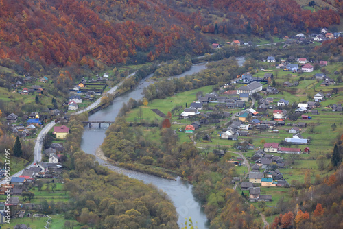 Scenic mountain village nestled beside a winding river in autumn foliage