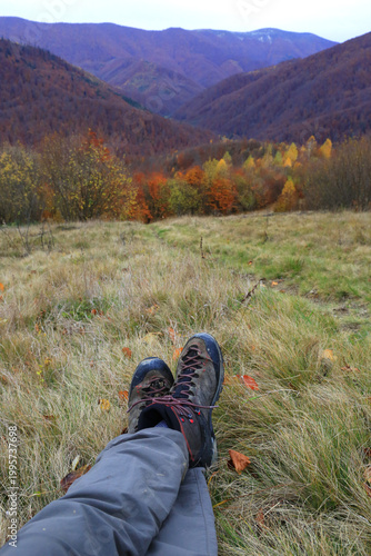 Relaxing in hiking boots with a view of autumn mountains and colorful trees