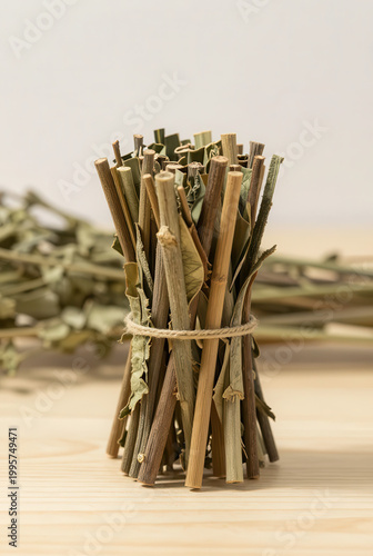 A bunch of fresh green asparagus rests on a rustic wooden table next to a glass aromatherapy diffuser bottle with bamboo incense sticks for a natural kitchen decoration