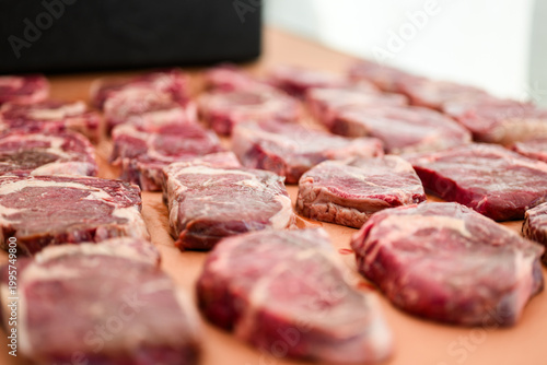 Rows of raw, marbled ribeye steaks laid out on butcher paper during a Steak Cookoff Association (SCA) BBQ competition, showcasing premium meat quality and preparation for professional grilling.