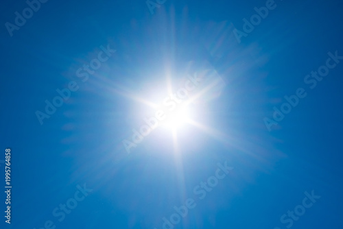 Canvas Print Brilliant sunburst with symmetrical light rays shining against a clear blue sky