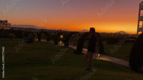 Silhouette Photographer Documenting Tranquil Sunset Over Resort Landscape At Golden Hour