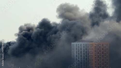 Thick black smoke over city buildings from large fire, environmental pollution and urban disaster concept